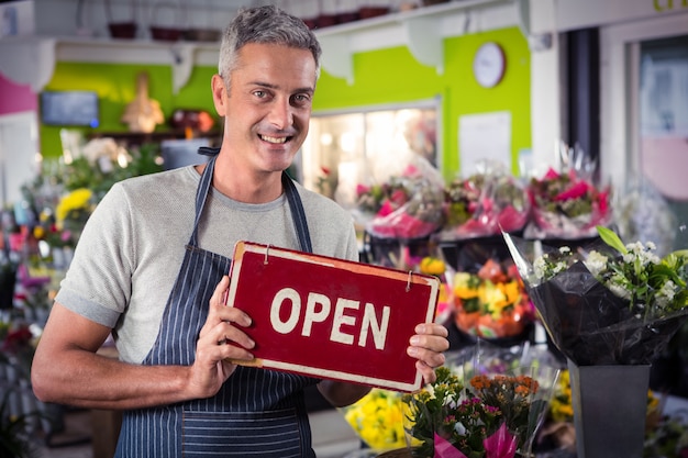 Mannelijke bloemist die open uithangbord houdt