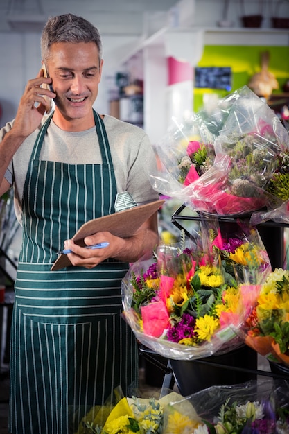 Mannelijke bloemist die orde op mobiele telefoon neemt