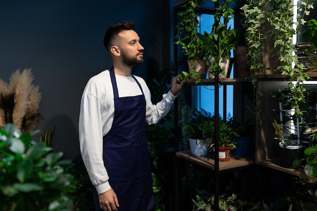 Mannelijke bloemist in het tuincentrum tegen de achtergrond van potplanten