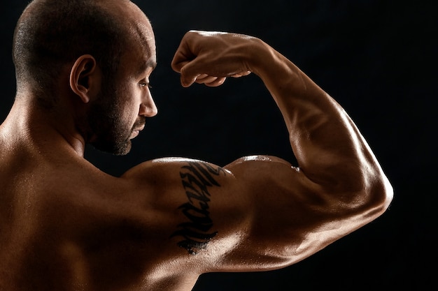 Mannelijke bodybuilder met lichte stoppels en blote torso toont gespierdheid