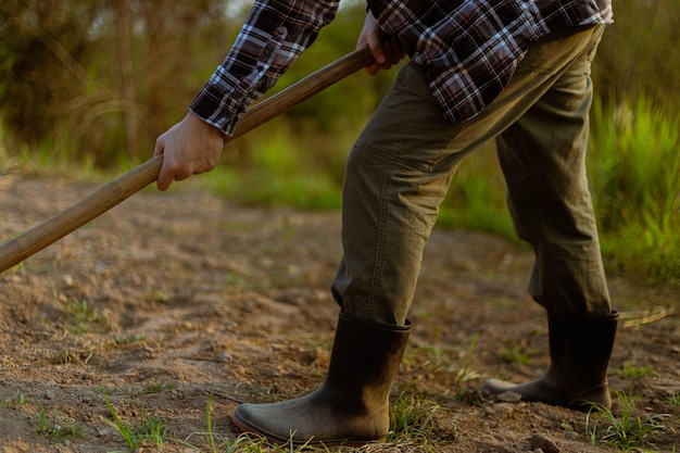 Mannelijke boer die een schoffel gebruikt die in de grond graaft voor het maken van moestuinen die zich voorbereiden op het kweken van planten
