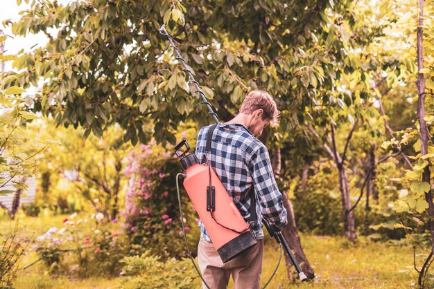 Mannelijke boer die spray-insecticidebescherming toepast op de boombladeren met behulp van pomp