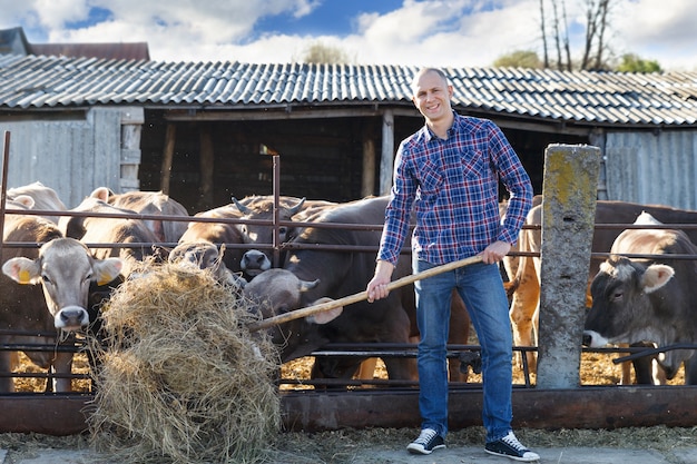 Foto mannelijke boer in een boerderij met vee op de achtergrond