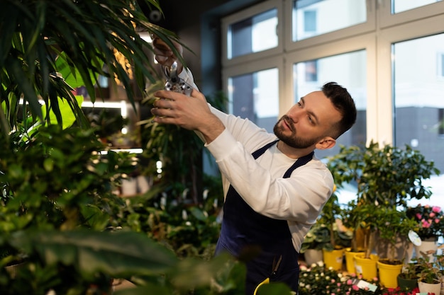 Mannelijke botanicus zorgt voor potplanten in het tuincentrum