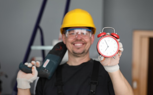 Mannelijke bouwerhelm die lacht met wekker