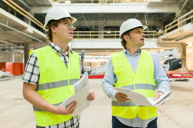 Mannelijke bouwvakker en ingenieur bij bouwwerf