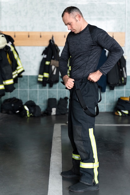 Foto mannelijke brandweerman verkleedt zich voor zijn werk