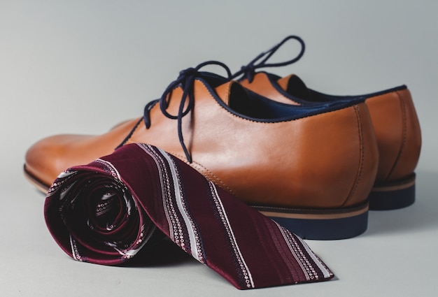 Mannelijke bruine schoenen met stropdas op grijze tafel
