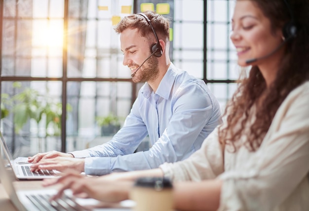 Foto mannelijke callcenteroperator met koptelefoon zit op een modern kantoor