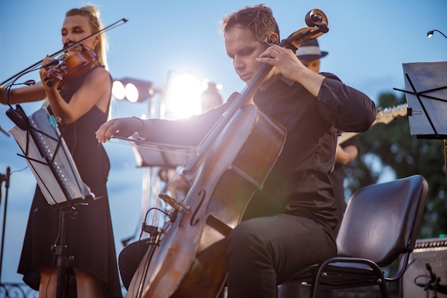 Mannelijke cellist die in orkest speelt bij openluchtconcert