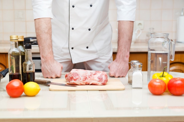 Mannelijke chef-kok bereidt filetvarkensvlees voor het koken bij restaurantkeuken