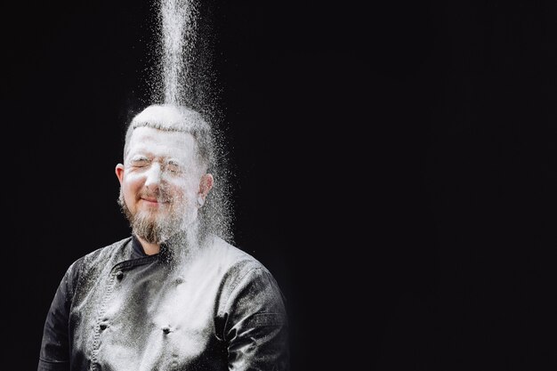 Mannelijke chef-kok die deeg in keuken maakt. Chef-kok Wordt Overgoten Met Bloem. Gelukkig bakker.