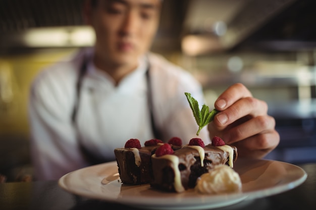 Mannelijke chef-kok die dessertbord versieren