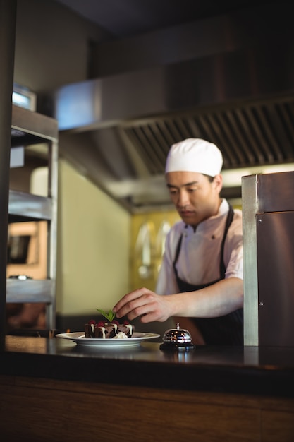 Mannelijke chef-kok die dessertbord versieren