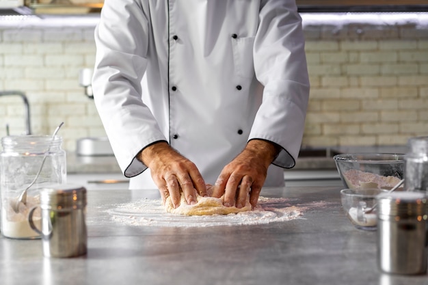 Foto mannelijke chef-kok in de keuken deeg kneden