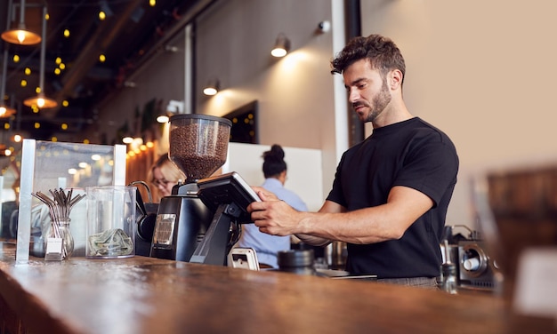 Mannelijke coffeeshopeigenaar die achter de verkoopbalie werkt