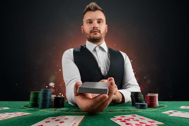 Mannelijke dealer in het casino aan tafel. Casinoconcept, gokken, poker, chips op de groene casinotafel.