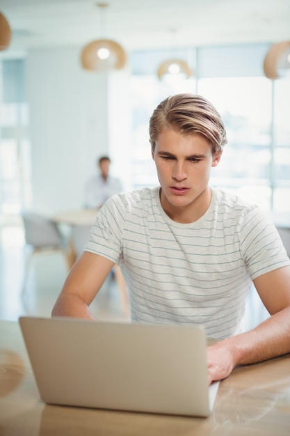 Mannelijke directeurzitting bij bureau en het gebruiken van laptop