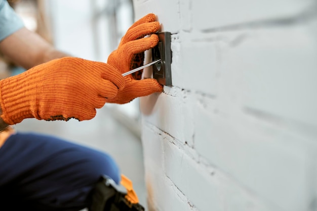 Mannelijke elektricienhanden die elektrisch stopcontact repareren