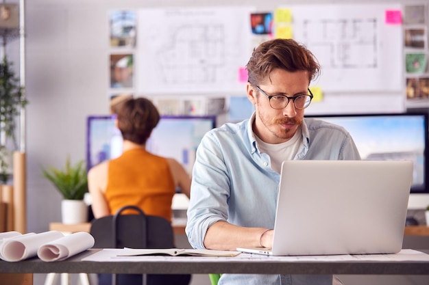 Mannelijke en vrouwelijke architecten in kantoor werken aan bureau op laptop- en desktopcomputers