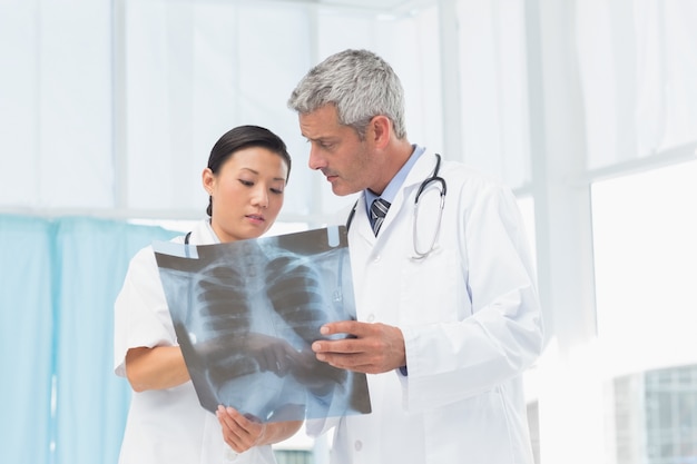 Mannelijke en vrouwelijke artsen die röntgenstraal onderzoeken