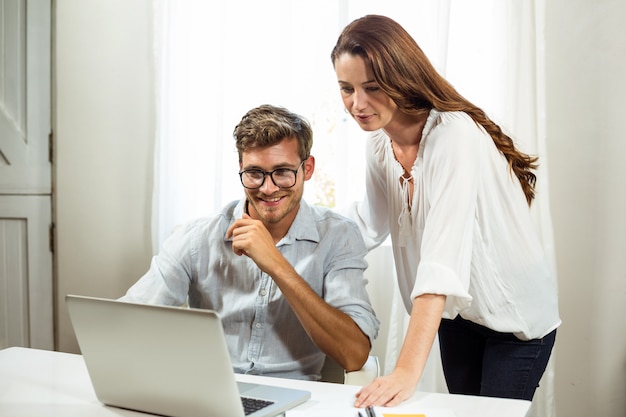 Mannelijke en vrouwelijke collega's die laptop met behulp van op kantoor