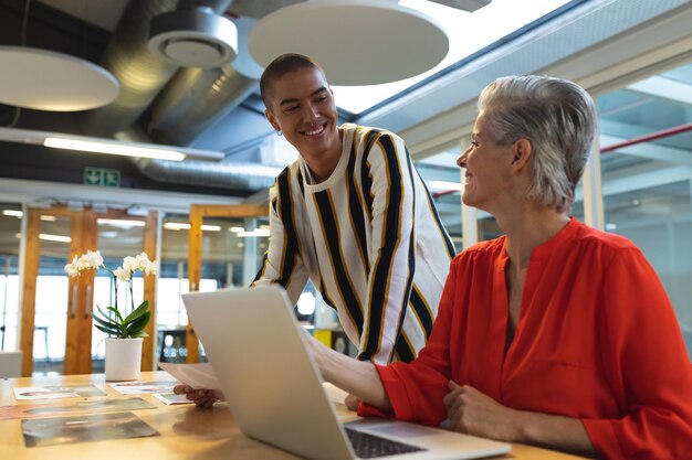 Mannelijke en vrouwelijke grafische ontwerpers bespreken foto's aan hun bureau