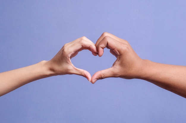 Mannelijke en vrouwelijke handen die een hartvorm vormen geïsoleerd op een grijze achtergrond