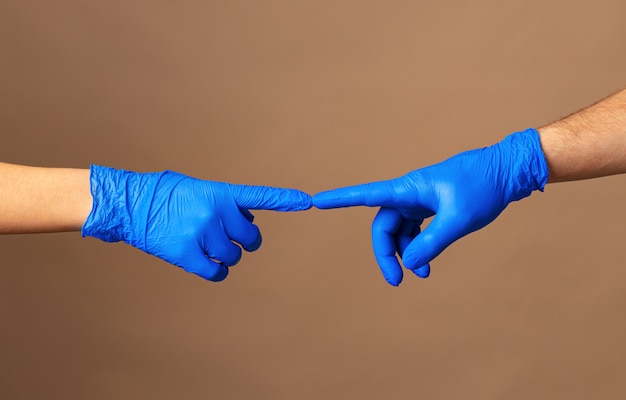 Foto mannelijke en vrouwelijke handen in medische handschoenen strekken tot elkaar. help concept. detailopname