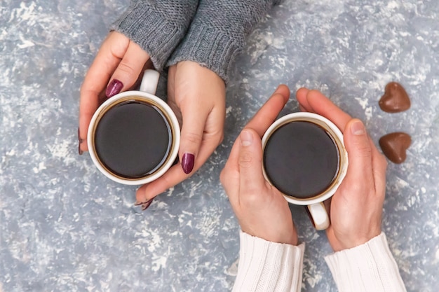 Mannelijke en vrouwelijke handen met kopjes koffie. Selectieve aandacht.