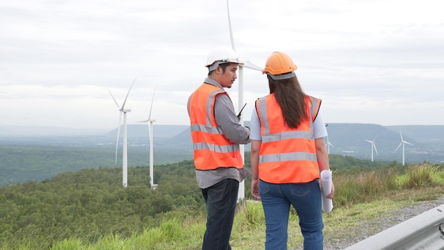 Mannelijke en vrouwelijke ingenieurs werken aan een windpark bovenop een heuvel of berg op het platteland Progressief ideaal voor de toekomstige productie van hernieuwbare duurzame energie