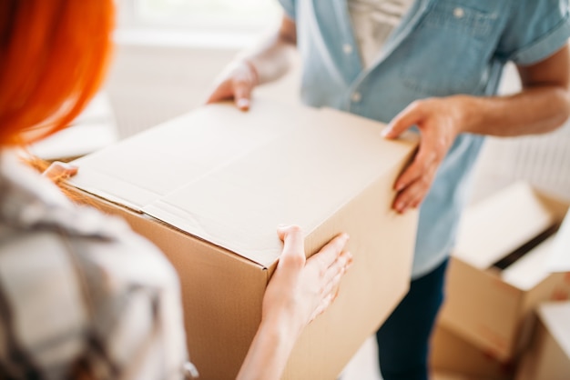 Mannelijke en vrouwelijke persoon handen houdt kartonnen doos, housewarming. Verhuizen naar een nieuw huis