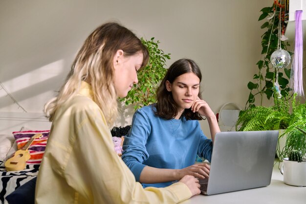 Mannelijke en vrouwelijke tienervrienden die laptop thuis gebruiken voor hun vrije tijd