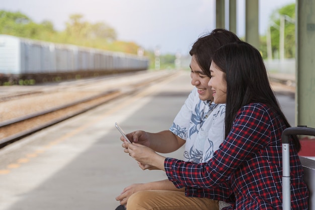 Mannelijke en vrouwelijke toeristen gebruiken tablets om hun reizen op het treinstation te plannen.