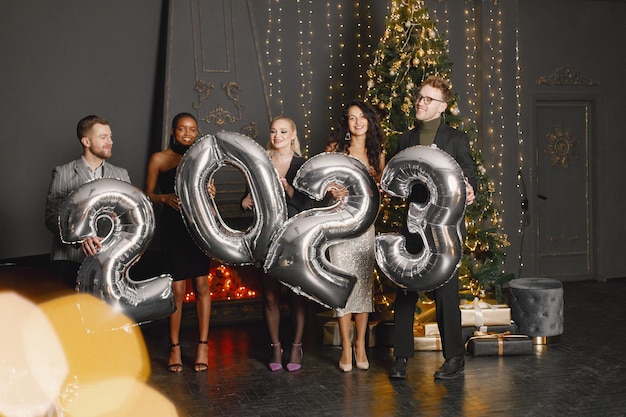 Mannelijke en vrouwelijke vrienden staan met ballonnen 2023 voor nieuwjaarsviering