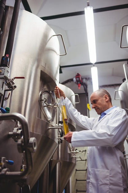 Foto mannelijke fabrikant die bier onderzoekt bij brouwerij