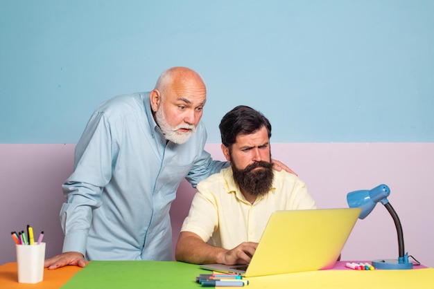 Mannelijke familie van meerdere generaties met behulp van internet senior man die laptop leert aan zijn oude zoon twee man in dif