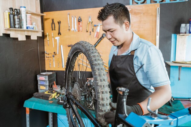 Mannelijke fietsenmaker in schort spant wiel aan terwijl probleem wordt opgelost