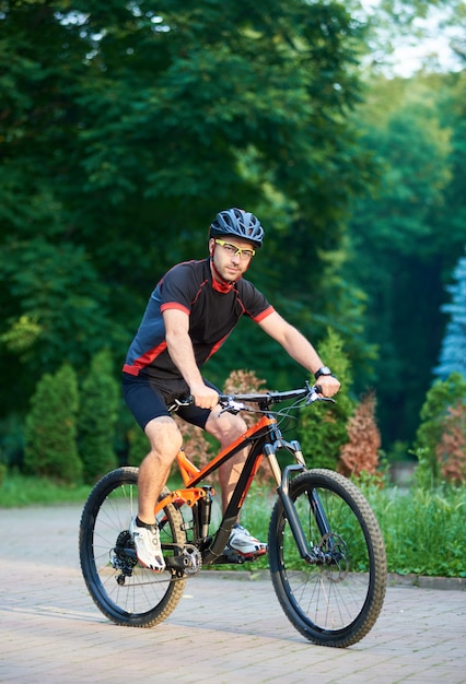 Mannelijke fietser berijdende fiets onderaan park bedekte steeg