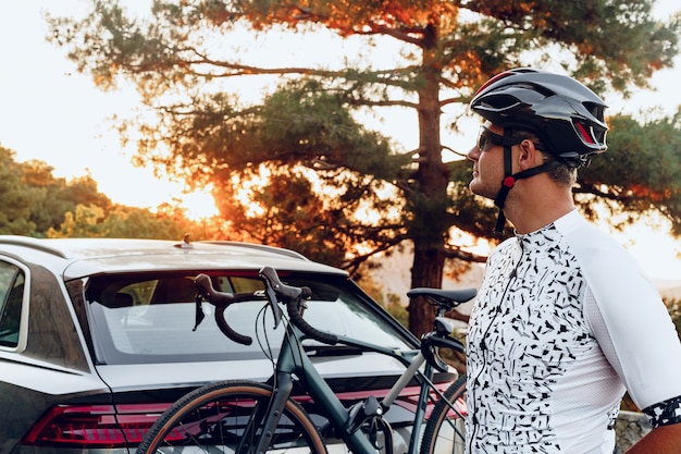 Mannelijke fietser die zijn fiets laadt op een rek van zijn crossover-auto na een rit