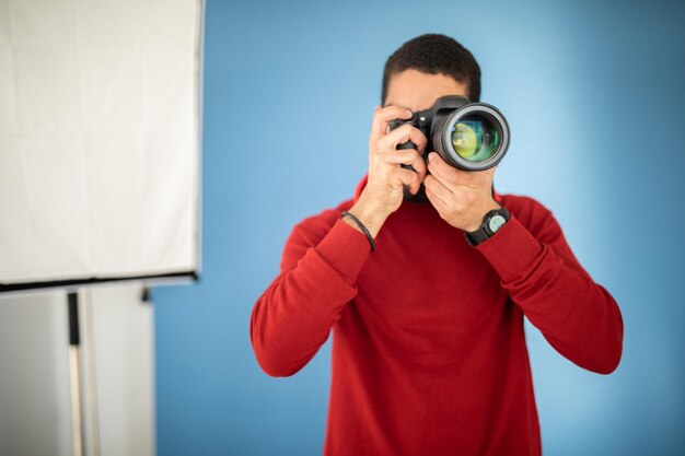 Mannelijke fotograaf die foto's maakt met digitale camera in de studio