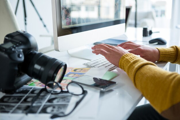 Mannelijke fotograaf die over computer bij bureau werkt