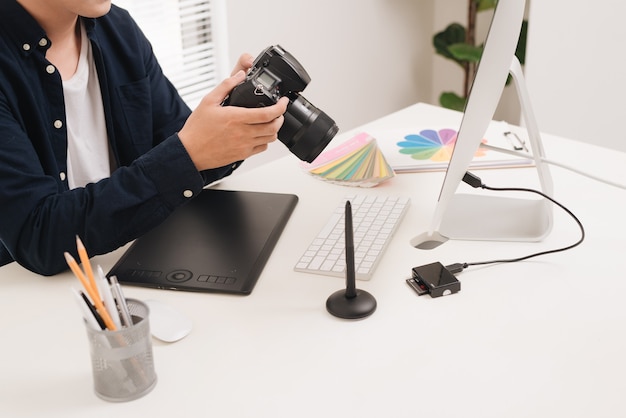 Mannelijke fotograaf, zittend aan zijn bureau, kijkend naar de camera