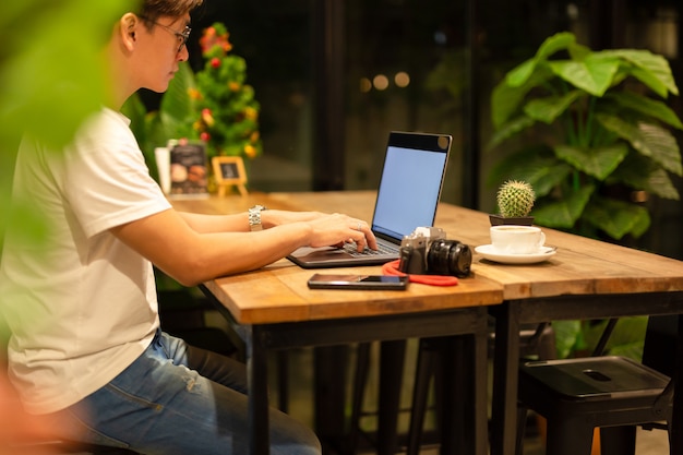 Mannelijke freelancer die aan laptop bij late nacht in koffiewinkel werken.