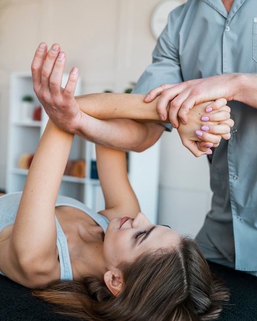 Mannelijke fysiotherapeut met vrouwelijke patiënt in de kliniek