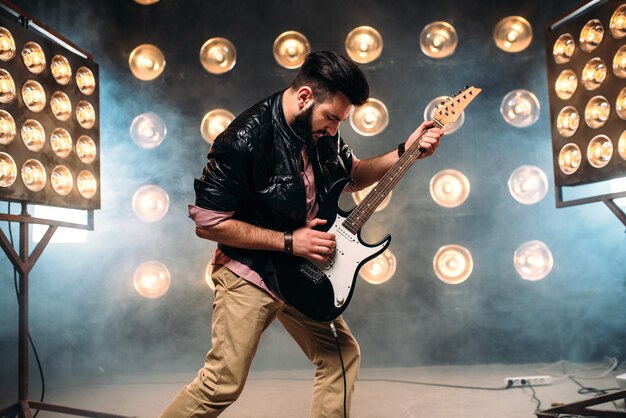 Mannelijke gitarist op het podium met decoraties van lichten