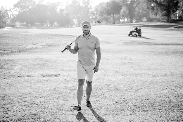 Mannelijke golfspeler op professionele cursus lopen op groen gras golfen