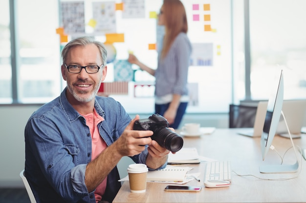 Mannelijke grafisch ontwerper die digitale camera houdt