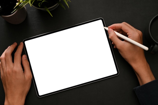 Mannelijke grafisch ontwerper die digitale tablet gebruikt met een styluspen op zwarte werkruimte