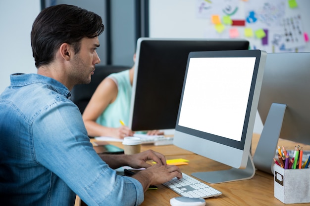 Mannelijke grafisch ontwerper die grafisch tablet gebruiken bij bureau